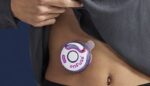 A patient wears the Enable Injections disc-shaped Enfuse device on their stomach.