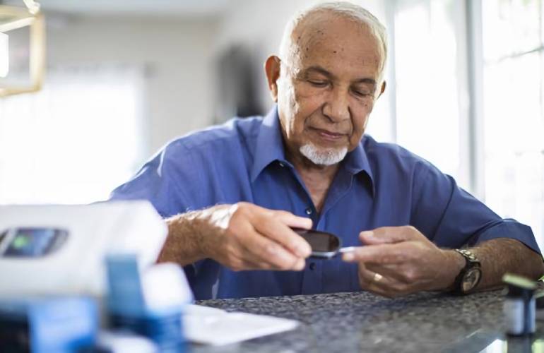 Philips Virtual Care Management Portfolio man takes blood glucose reading at home
